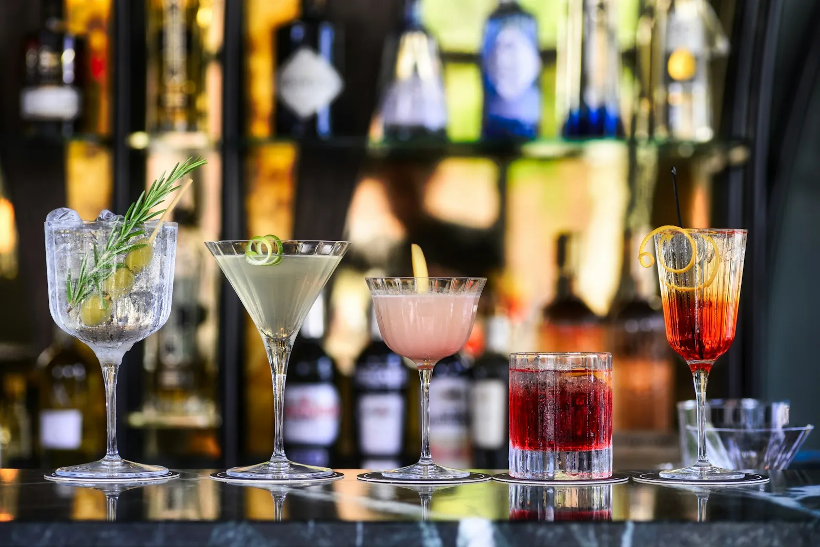 Cocktail colorati allineati sul bancone di un bar